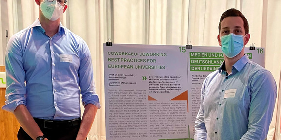 JProf. Dr. Simon Hensellek und Jonah Weißwange vor dem Cowork4EU Poster auf der Global Gallery 2022